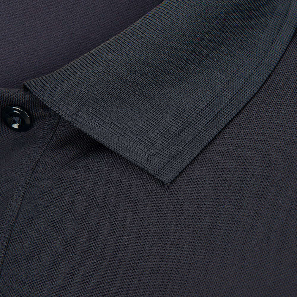 Close-up detail of a dark charcoal polo shirt collar showing ribbed knit texture and a single dark button a finely stitched seam and a subtle tonal contrast