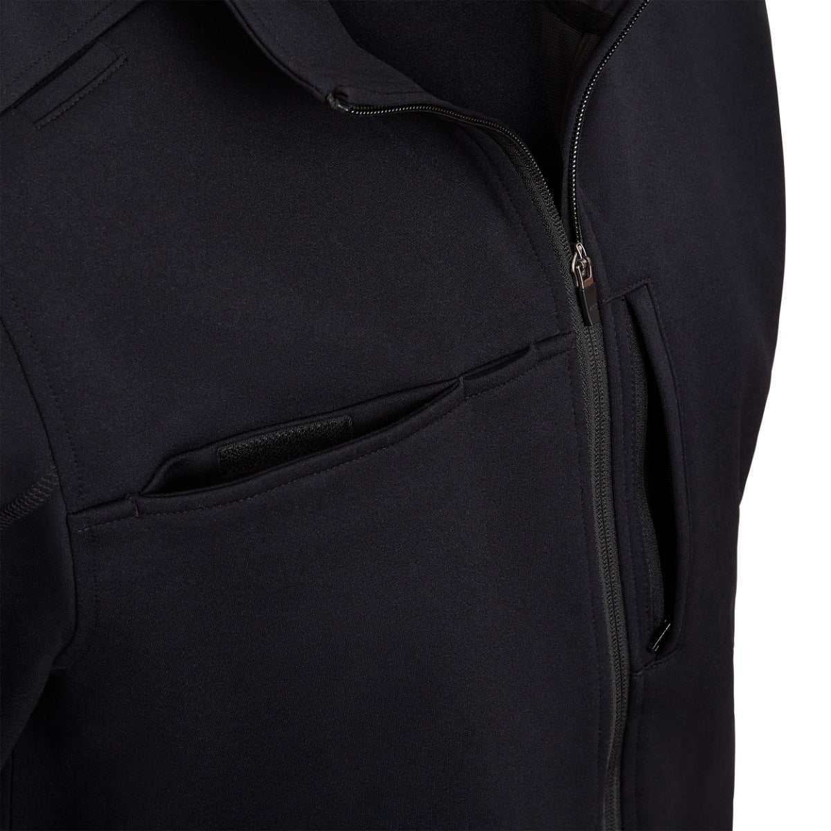 Close-up product shot of a black soft-shell jacket featuring a zipper, two welt pockets, and subtle textured fabric
