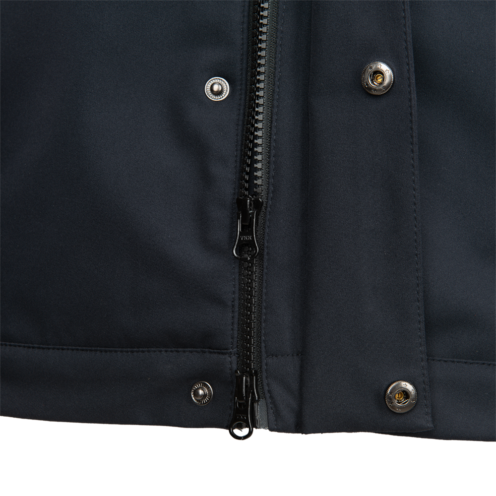 Close-up detail shot of a dark navy blue jacket showing a YKK zipper, silver metallic buttons and subtle stitching