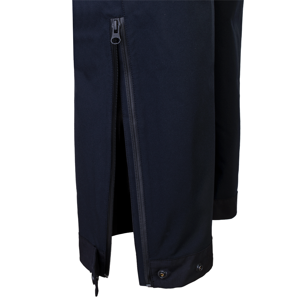 Close-up product shot of dark navy softshell pants featuring a full-length center zipper, snap closures at the hem, and subtle branding details