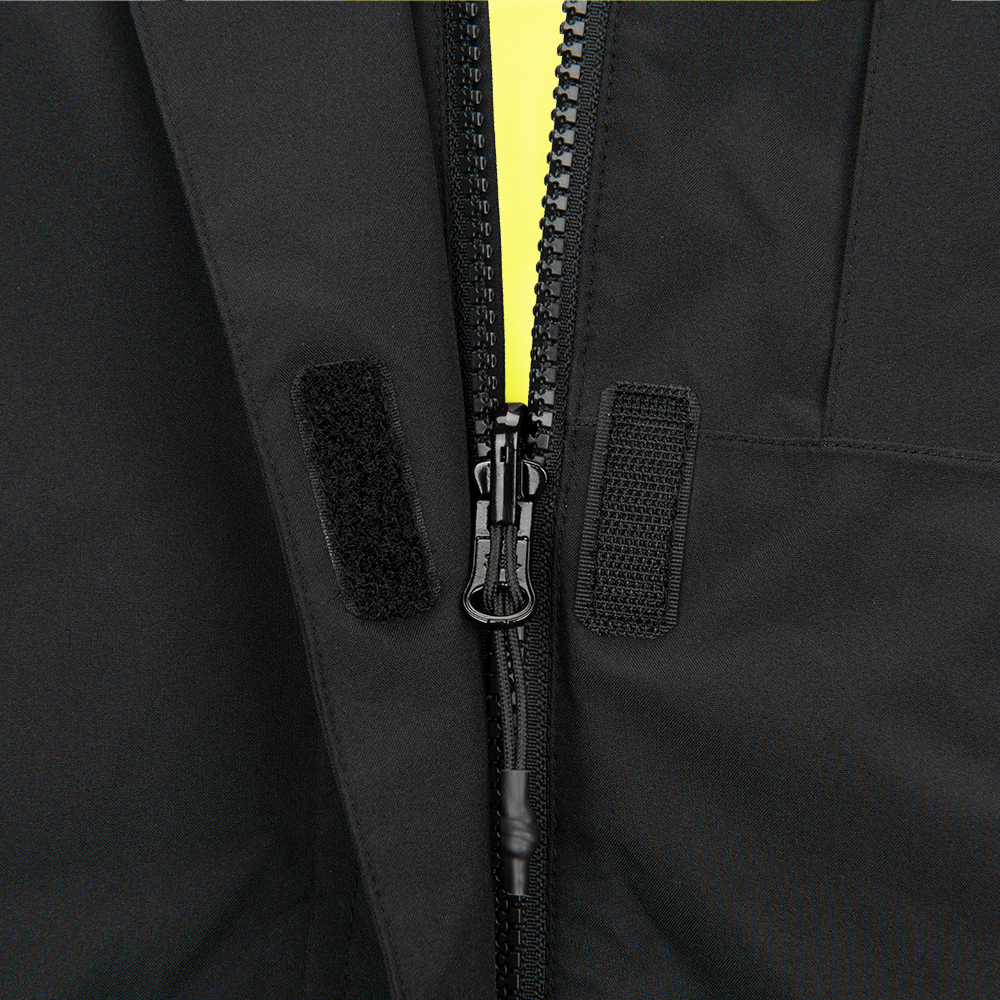 Close-up photograph showing a black jacket detail with a bright yellow zipper and black velcro closures