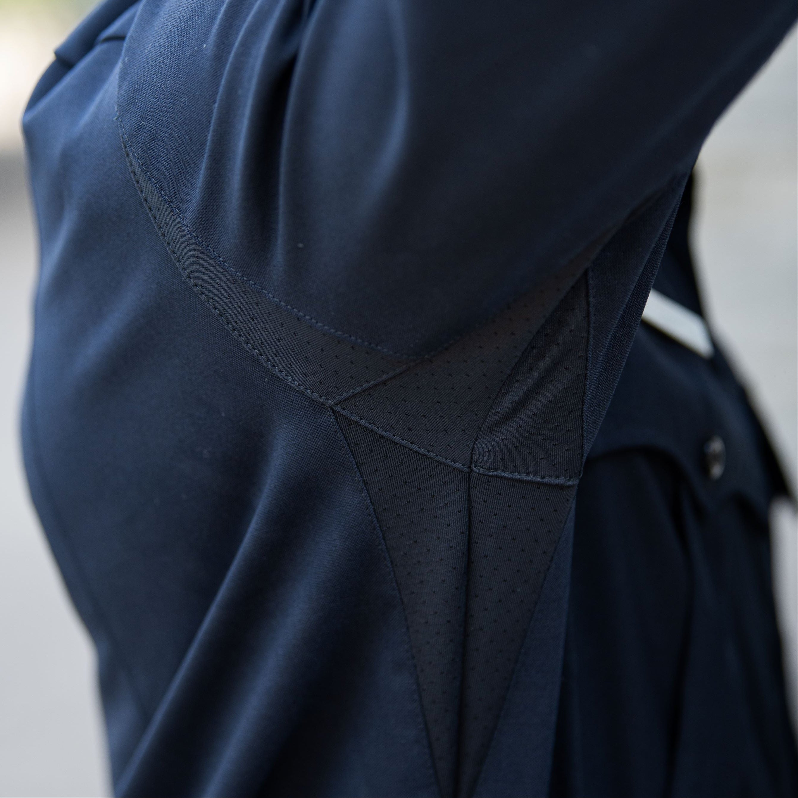 Close-up photograph of a navy blue shirt detail showing breathable mesh panels and unique stitching