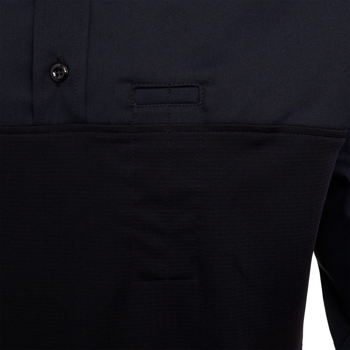 Close-up of a navy blue men's polo shirt showcasing a textured fabric, a small hidden pocket, and a contrasting button detail