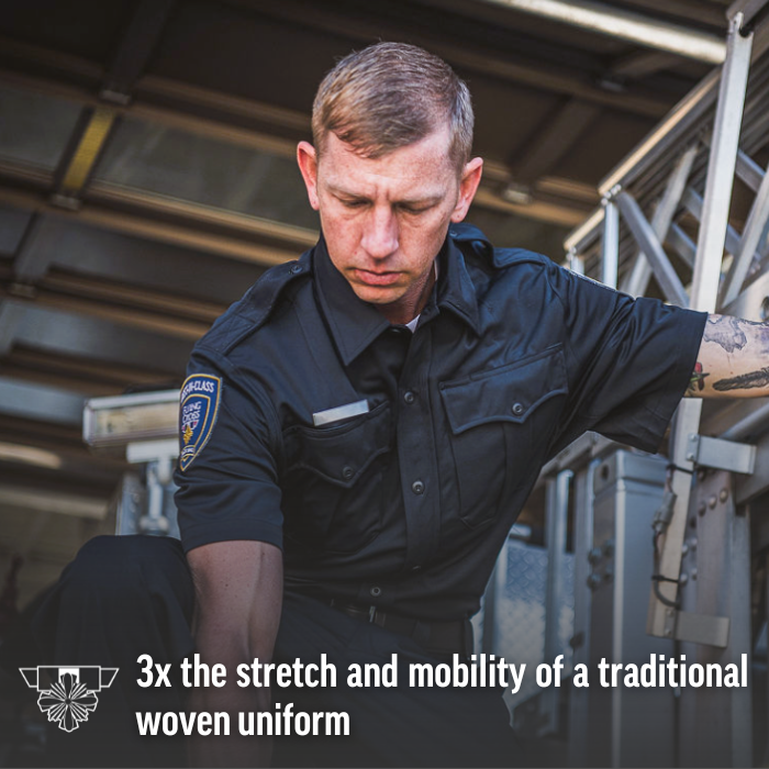 Photograph of a firefighter in a dark uniform with a patch, inside a firetruck, featuring a visible ladder, a serious expression, and a sleeve tattoo
