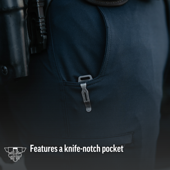 Close-up photograph showing a dark-colored garment with a knife-notch pocket and a metallic clip detail featuring subtle stitching and a dark background