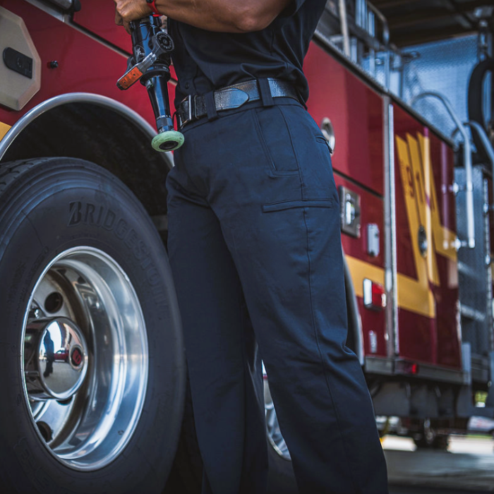 Photograph firefighter near firetruck with shiny silver wheel Bridgestone tire and a lime green nozzle detail