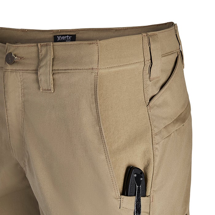 Close-up product shot of tan Xvertx tactical pants showing a knife in a pocket with detailed stitching and a branded waistband