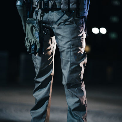 Photograph unknown artist a person wearing tactical pants and gloves at night with out of focus lights in the background showing cargo pockets and textured fabric
